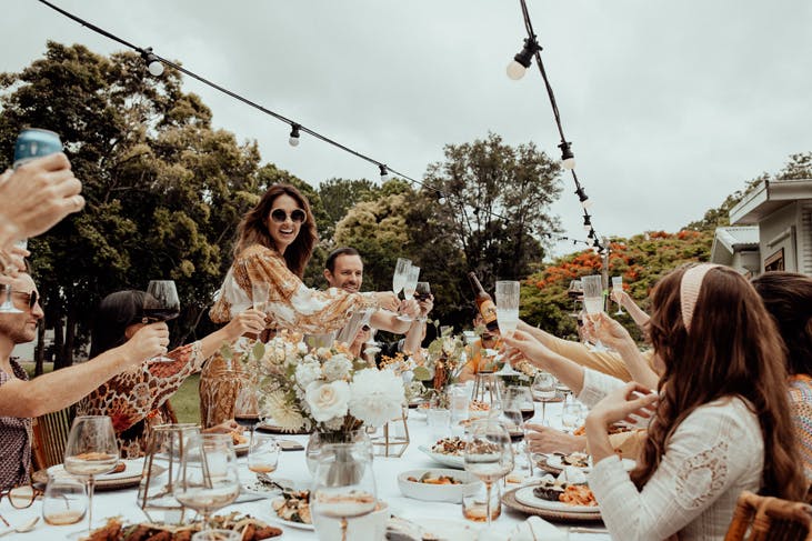 A party of people cheers around an outdoor table